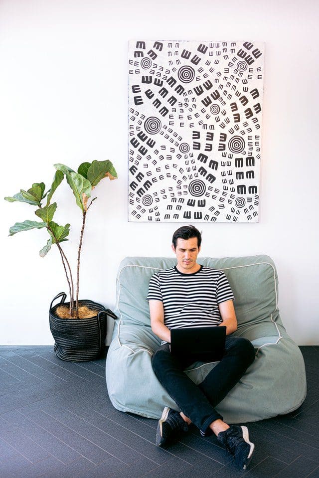 man sitting on bean bag on laptop