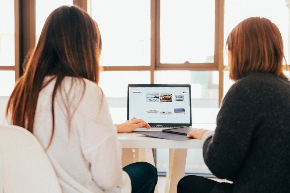 two women sat looking at laptop